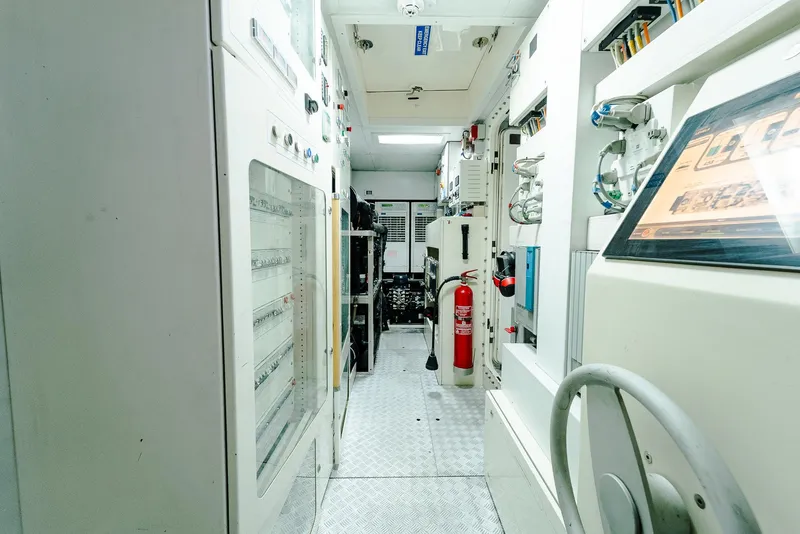 Slide: The Image of Engine room of a 2012 Custom Line 100 yacht, featuring control panels and safety equipment. - 49