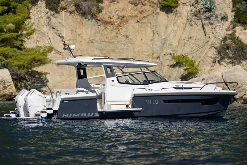 Slide: The Image of 2025 Nimbus W11 boat cruising near rocky shoreline with lush greenery. - 6