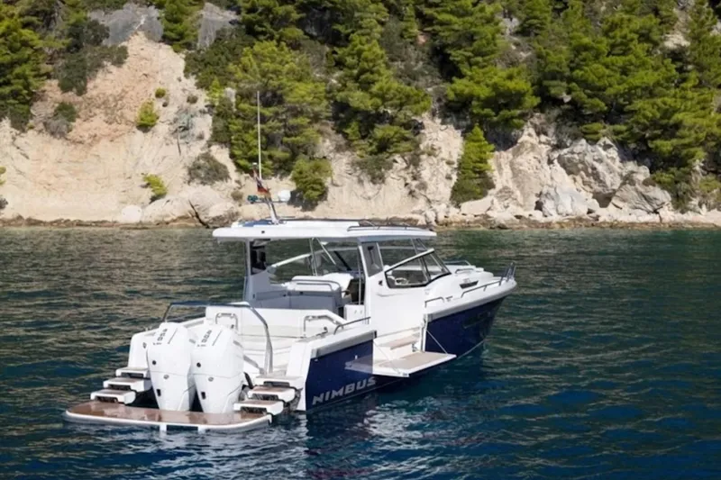 Slide: The Image of Nimbus W11 2025 boat on clear water near rocky, forested shoreline. - 8