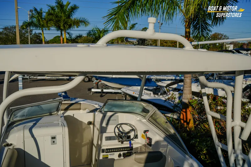 Slide: The Image of 2022 Key West 239 DFS boat interior with steering wheel, parked near palm trees. - 21