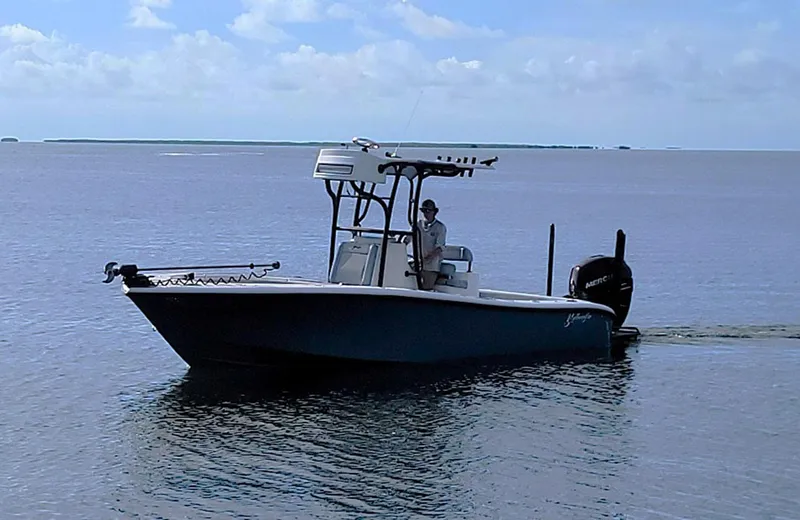Slide: The Image of 2021 Yellowfin 26 Hybrid boat on calm water under a clear sky. - 6
