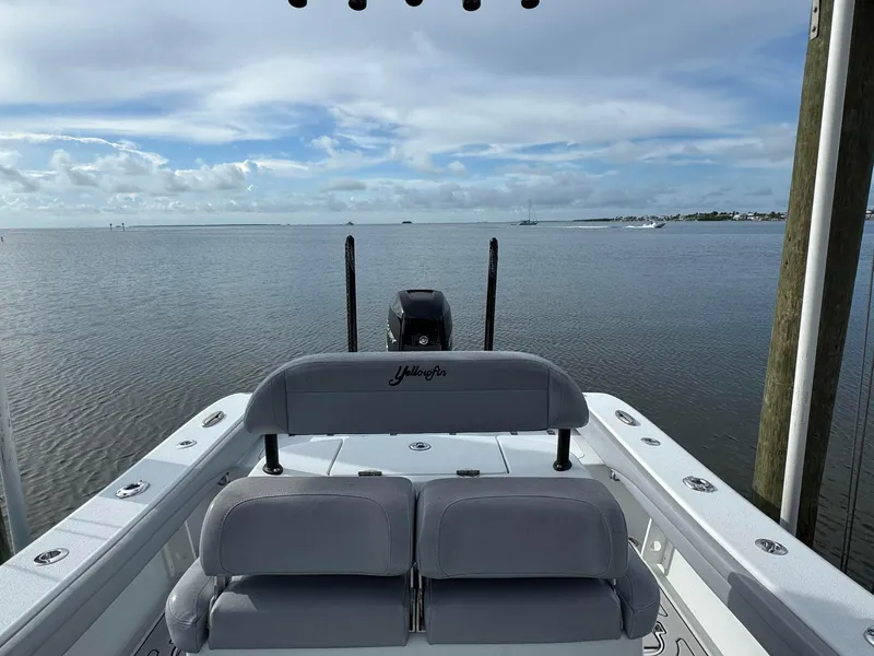 Slide: The Image of 2021 Yellowfin 26 Hybrid boat on calm water, showcasing rear seating and motor. - 24