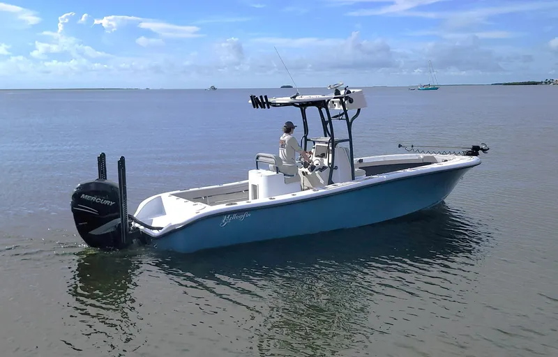 Slide: The Image of 2021 Yellowfin 26 Hybrid boat on calm water, featuring a Mercury outboard motor. - 1