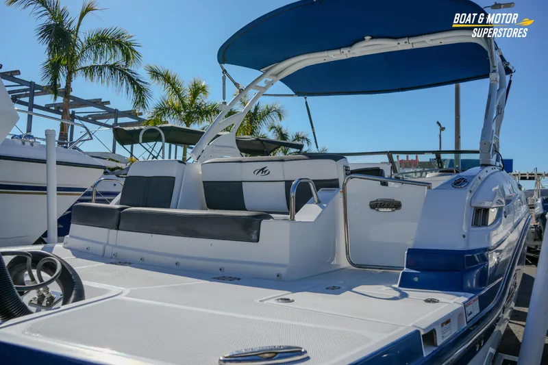 Slide: The Image of 2020 Monterey M-65 boat with blue canopy, docked under palm trees. - 11