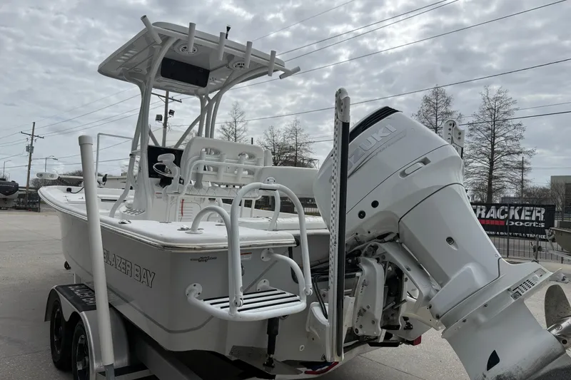 Slide: The Image of 2021 Blazer Bay 2400 boat with Suzuki outboard motor on trailer, parked outdoors. - 4