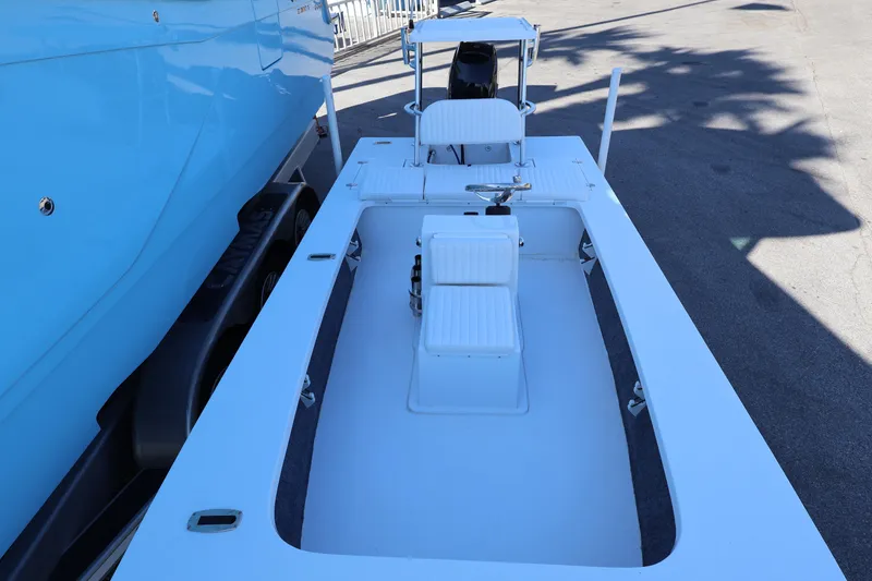 Slide: The Image of 2026 Mitzi Skiffs 17 Tournament boat, white deck, blue hull, parked outdoors. - 17