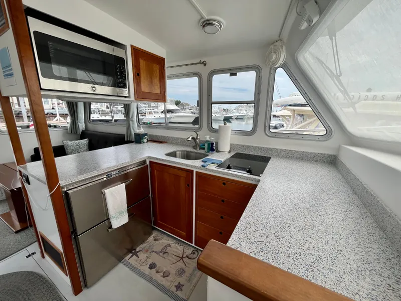 Slide: The Image of 2016 Wesmac 42 boat interior with modern kitchen, featuring wood cabinets and stainless steel appliances. - 25