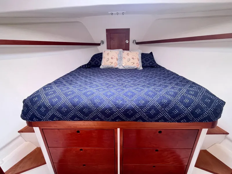 Slide: The Image of Cozy cabin interior of 2016 Wesmac 42 with blue bedding and wooden drawers. - 44