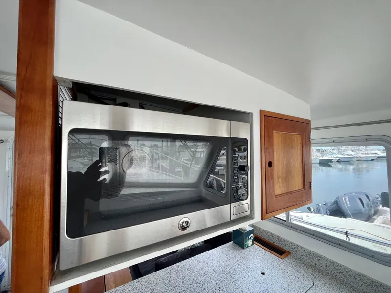 Slide: The Image of Microwave in 2016 Wesmac 42 boat kitchen with wooden cabinets and window view. - 27
