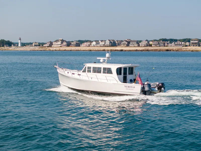 Slide: The Image of 2016 Wesmac 42 boat cruising near a coastal town with a lighthouse. - 2