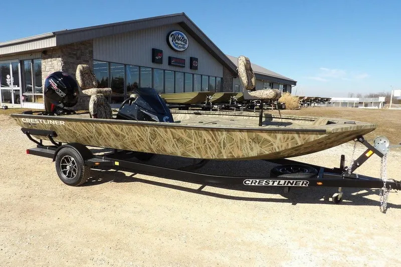 The Image of 2026 Crestliner XFC 189 boat with camouflage design on a trailer outside a marine center. - 1