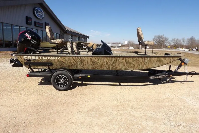 Slide: The Image of 2026 Crestliner XFC 189 fishing boat on trailer, camo design, parked outdoors. - 2