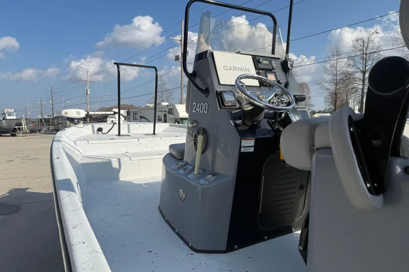 Slide: The Image of 2022 Blazer Bay 2400 boat with Garmin navigation, steering console, and seating under a clear sky. - 6