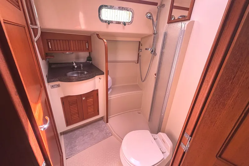 Slide: The Image of Luxurious 2006 Island Packet 440 yacht bathroom with shower, sink, and wooden cabinetry. - 21