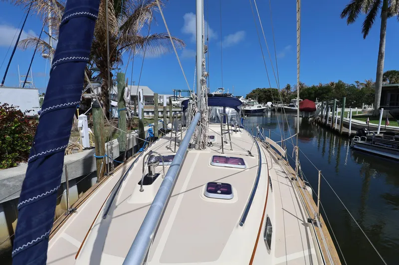 Slide: The Image of 2006 Island Packet 440 sailboat docked in a sunny marina, surrounded by palm trees. - 34