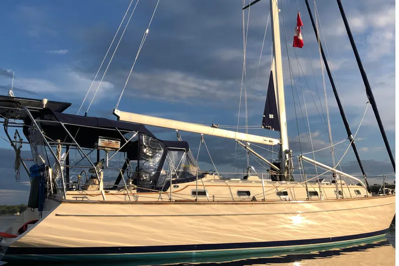 Slide: The Image of 2006 Island Packet 440 sailboat with blue canopy, docked under a cloudy sky. - 41