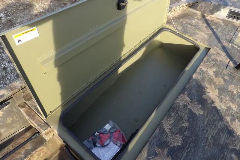 Slide: The Image of Open storage compartment in 2026 Crestliner XF 189 boat, featuring camouflage flooring. - 26