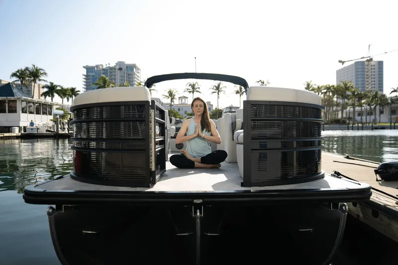 Slide: The Image of A woman meditates on a Harris Sunliner 230 pontoon boat in an urban marina. - 14