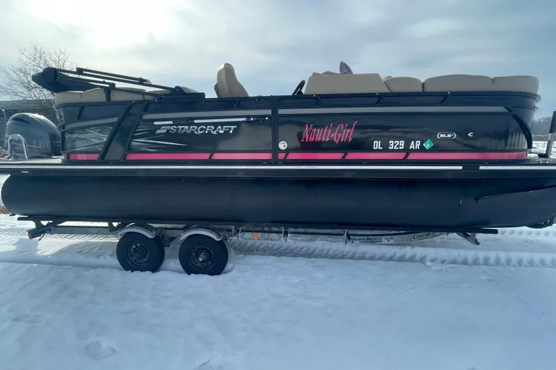 The Image of 2019 Starcraft SLS 3 pontoon boat on trailer, named "Nauti-Girl," in snowy setting. - 1