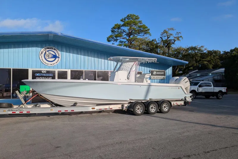 Slide: The Image of 2026 Contender 32 ST boat on trailer, parked near blue building under clear sky. - 2