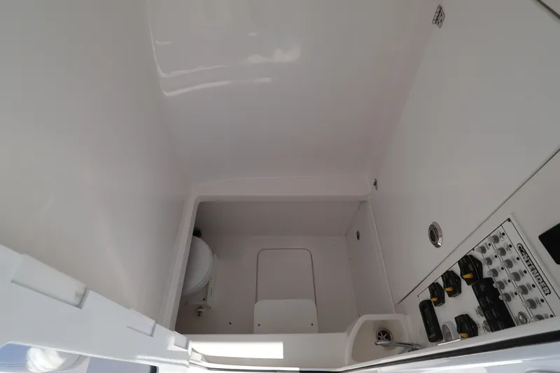 Slide: The Image of Interior of 2026 Contender 32 ST boat, featuring a compact marine toilet and control panel. - 34