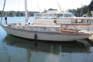 The Image of 1962 Kettenburg Sloop sailing near a forested shoreline. - 0