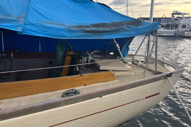 Slide: The Image of 1962 Kettenburg Sloop with blue tarp cover docked at marina. - 3