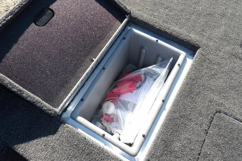 Slide: The Image of Storage compartment in 2026 Crestliner XF 189 boat, featuring carpeted interior and organized contents. - 16