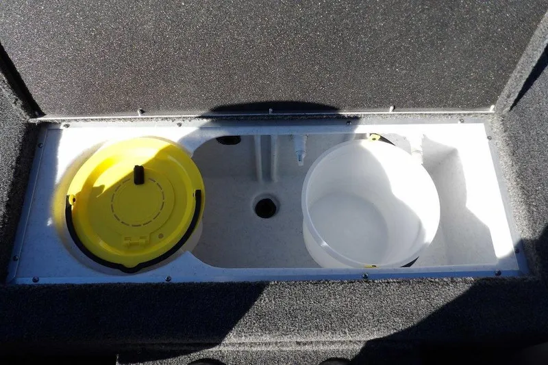Slide: The Image of 2026 Crestliner XFC 189 boat storage compartment with yellow lid and white bucket. - 16