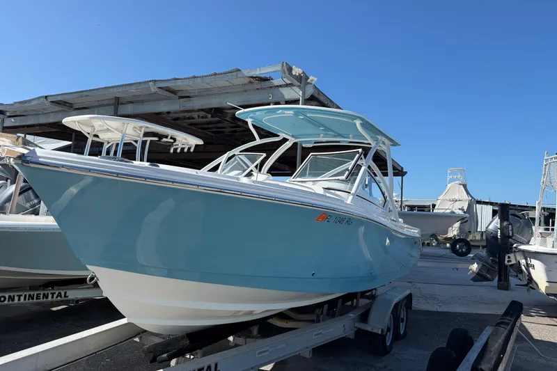 The Image of 2017 Edgewater 248CX Crossover boat on trailer, light blue hull, docked outdoors. - 1