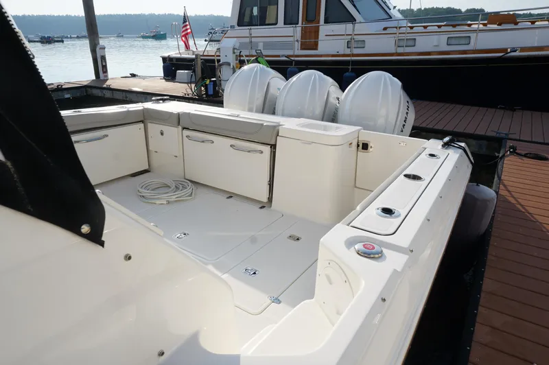 Slide: The Image of 2023 Pursuit OS 355 Offshore boat docked, featuring spacious deck and triple outboard engines. - 11