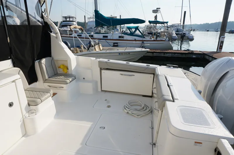 Slide: The Image of 2023 Pursuit OS 355 Offshore boat interior at marina, featuring seating and storage. - 3