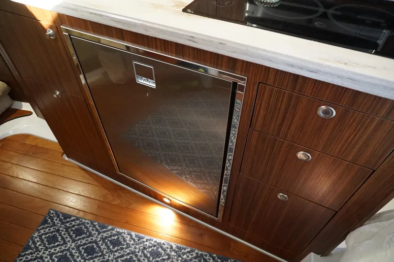 Slide: The Image of 2023 Pursuit OS 355 Offshore yacht kitchen with wood cabinetry and compact fridge. - 41