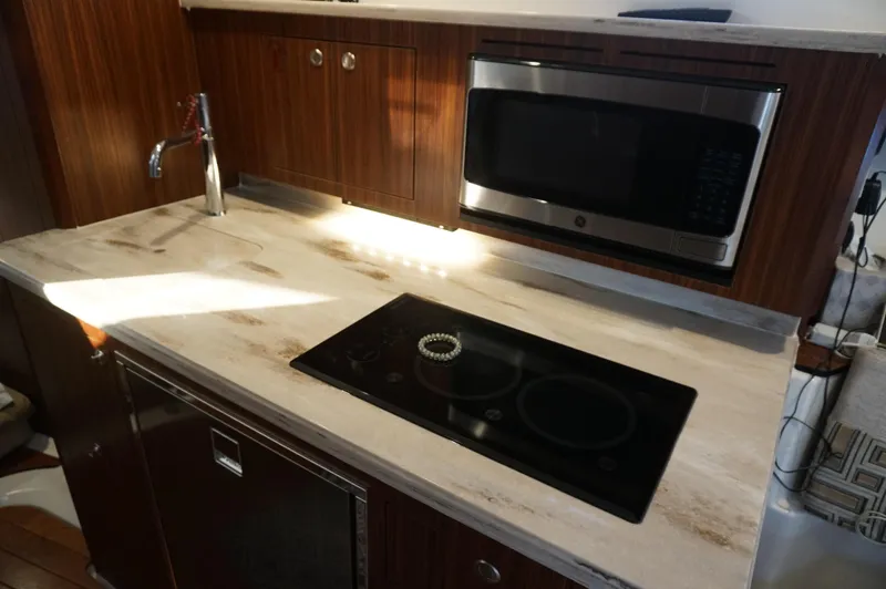 Slide: The Image of 2023 Pursuit OS 355 Offshore yacht kitchen with stove, microwave, and wooden cabinetry. - 42