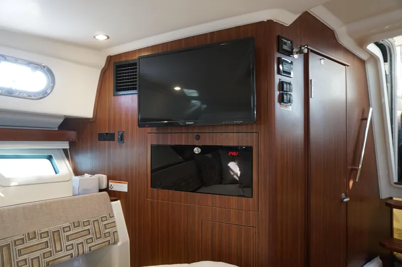 Slide: The Image of 2023 Pursuit OS 355 Offshore cabin interior with TV and wood paneling. - 44
