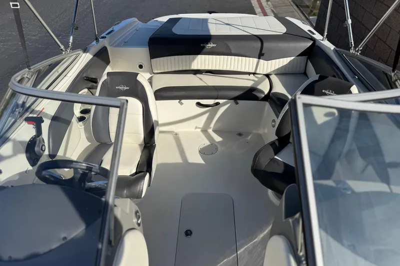 Slide: The Image of 2018 Stingray 208 LS boat interior with black and white seating, steering wheel, and cup holders. - 18