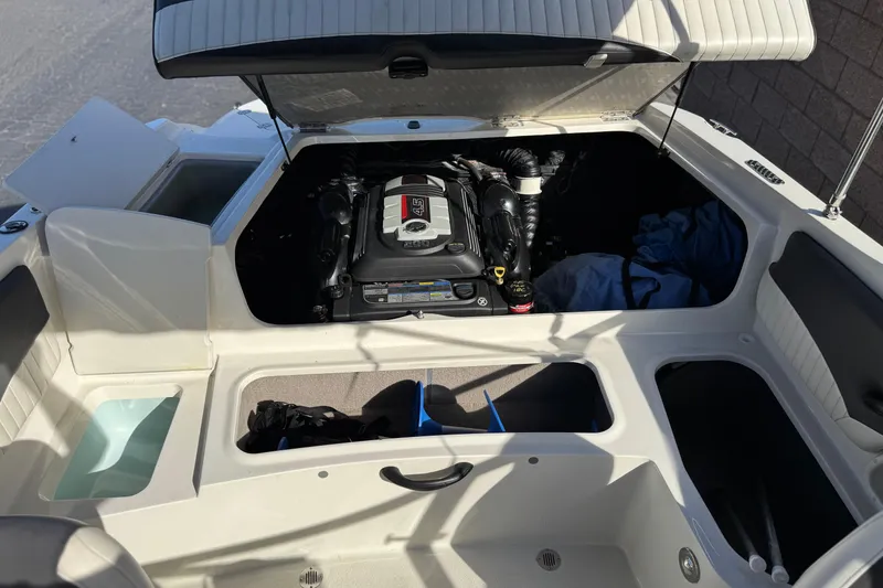 Slide: The Image of 2018 Stingray 208 LS boat engine compartment with open storage areas and seating. - 20