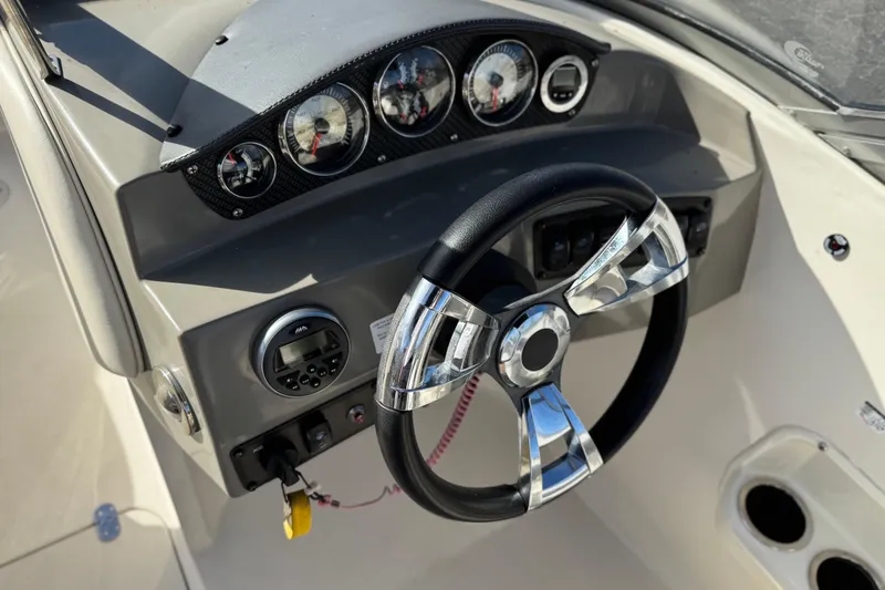 Slide: The Image of Steering wheel and dashboard of 2018 Stingray 208 LS boat, featuring modern gauges and controls. - 26