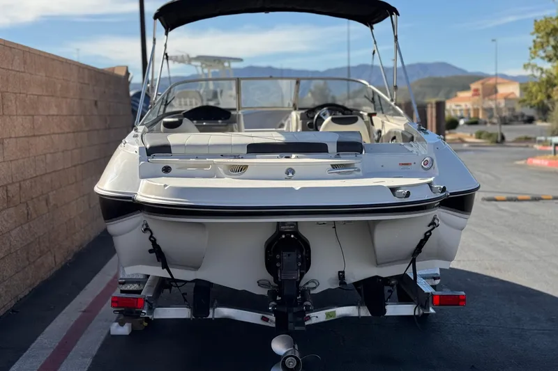 Slide: The Image of 2018 Stingray 208 LS boat on trailer, parked outdoors with mountains in background. - 4