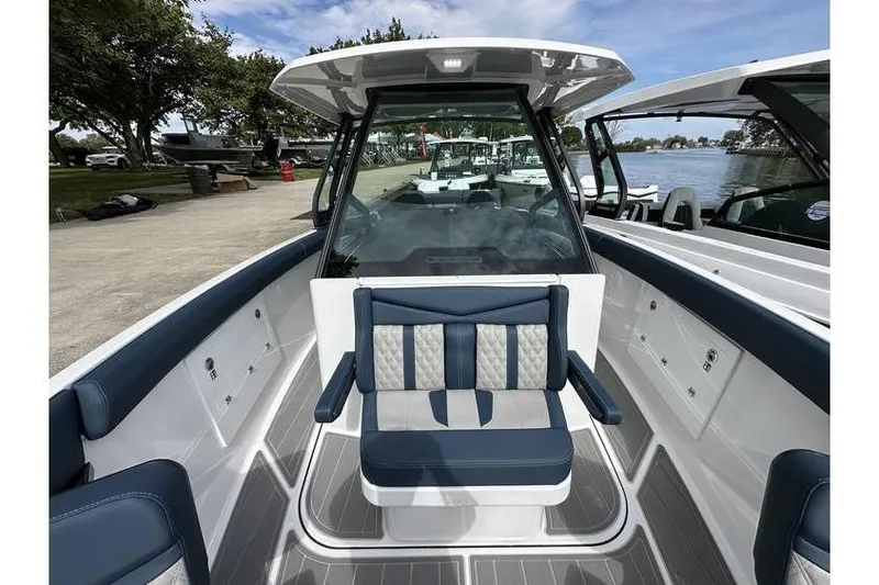 Slide: The Image of 2026 Monterey Elite 30 OB boat interior with blue and white seating, docked by a lake. - 12