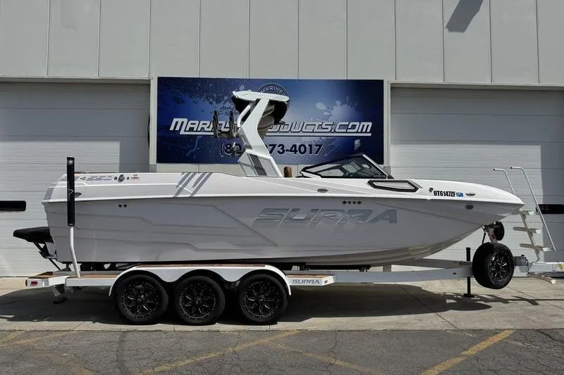 The Image of 2024 Supra SE 575 boat on trailer, parked outside a building. - 1