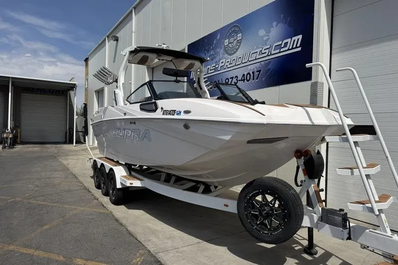 Slide: The Image of 2024 Supra SE 575 boat on trailer outside marine products store. - 3