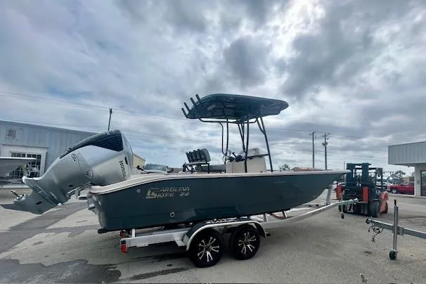 Slide: The Image of 2026 Carolina Skiff 22 Ultra Elite boat on trailer, parked outdoors under cloudy sky. - 14