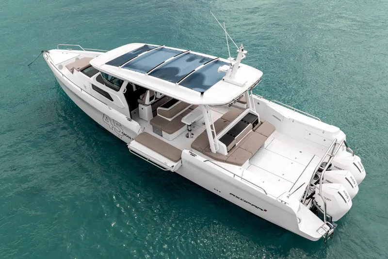Slide: The Image of 2025 Axopar 45 Cross Top boat on clear turquoise water, showcasing sleek design and triple engines. - 11