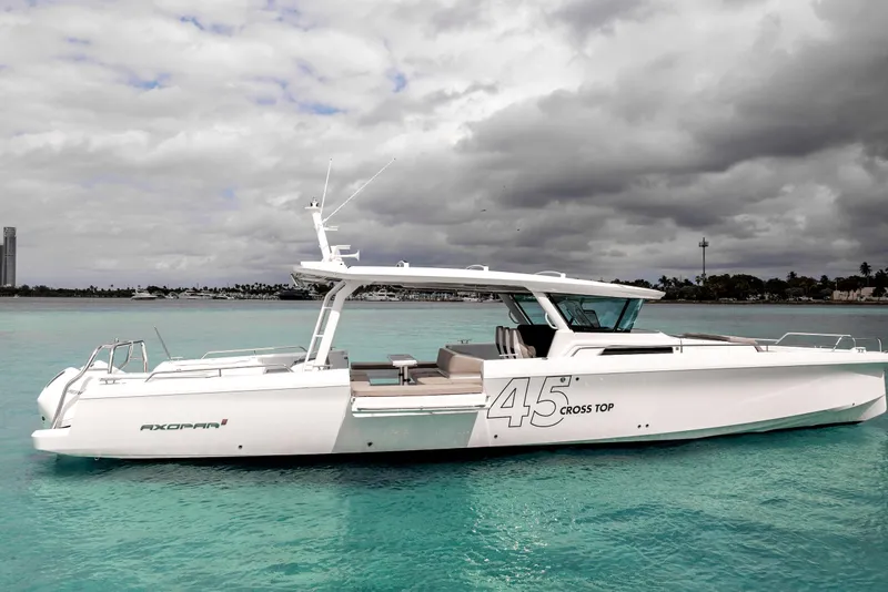 Slide: The Image of 2025 Axopar 45 Cross Top boat on turquoise water under cloudy sky. - 15