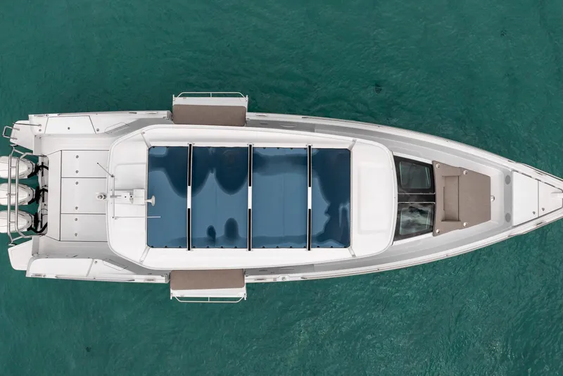 Slide: The Image of 2025 Axopar 45 Cross Top boat, aerial view, on clear turquoise water. - 19