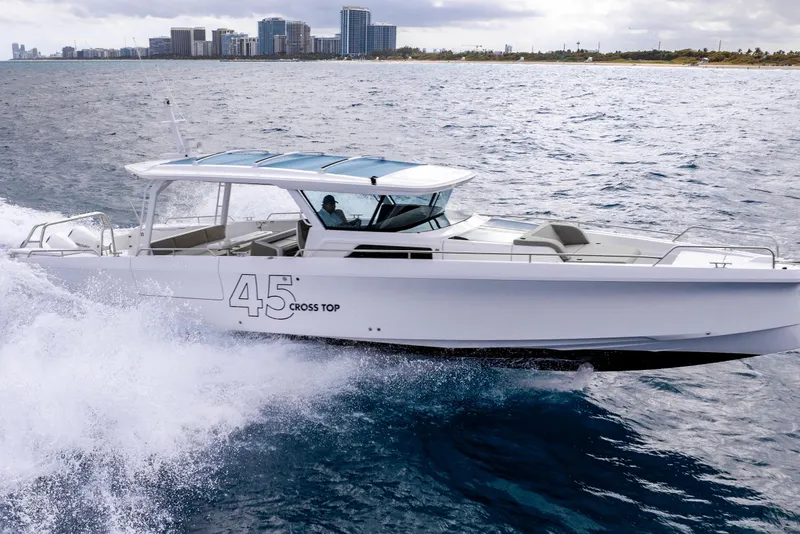 Slide: The Image of 2025 Axopar 45 Cross Top cruising on ocean near city skyline. - 31