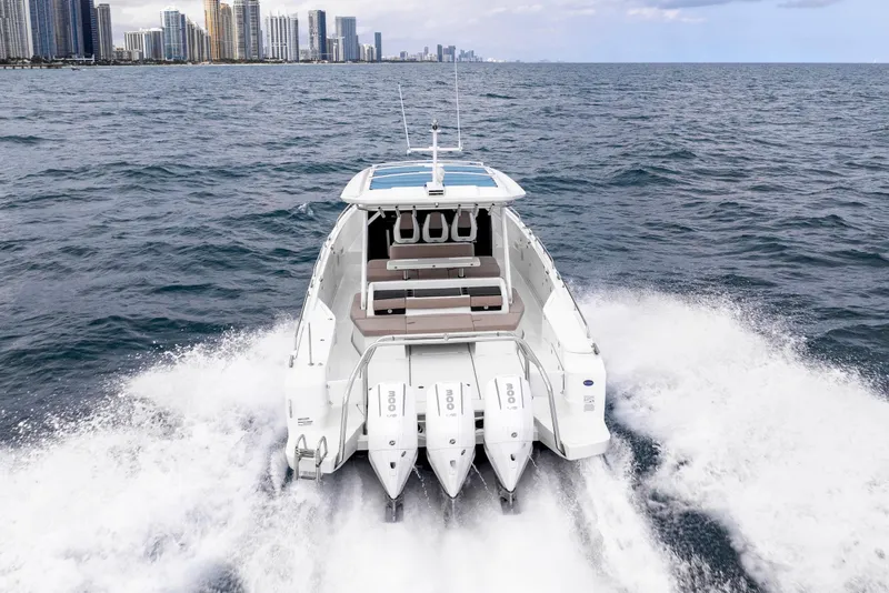 Slide: The Image of 2025 Axopar 45 Cross Top boat cruising on open water near city skyline. - 35