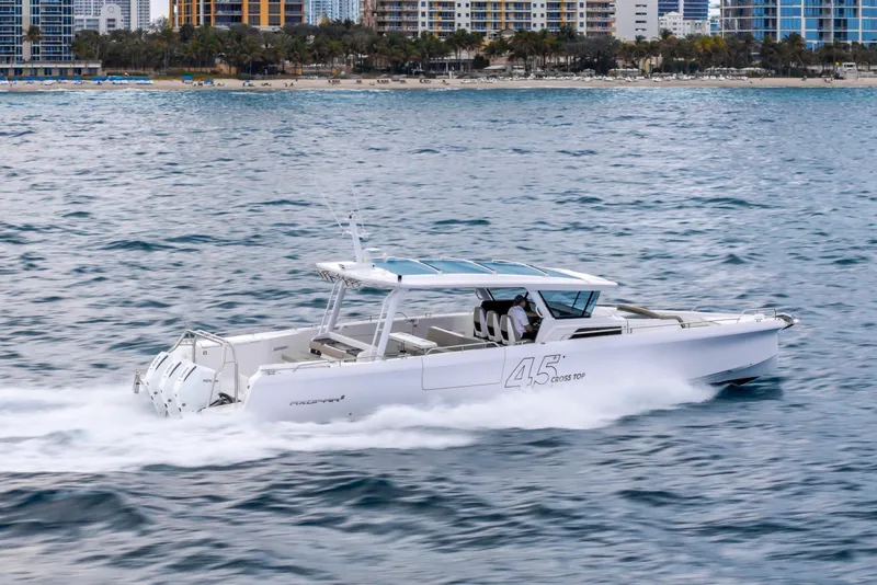 Slide: The Image of 2025 Axopar 45 Cross Top cruising on the ocean near a city shoreline. - 39
