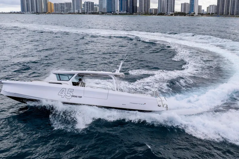 Slide: The Image of 2025 Axopar 45 Cross Top boat cruising near city skyline. - 40